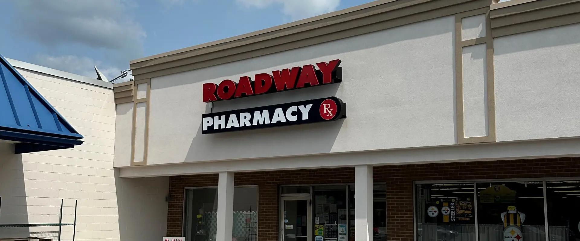 A pharmacy sign is lit up on the side of a building.